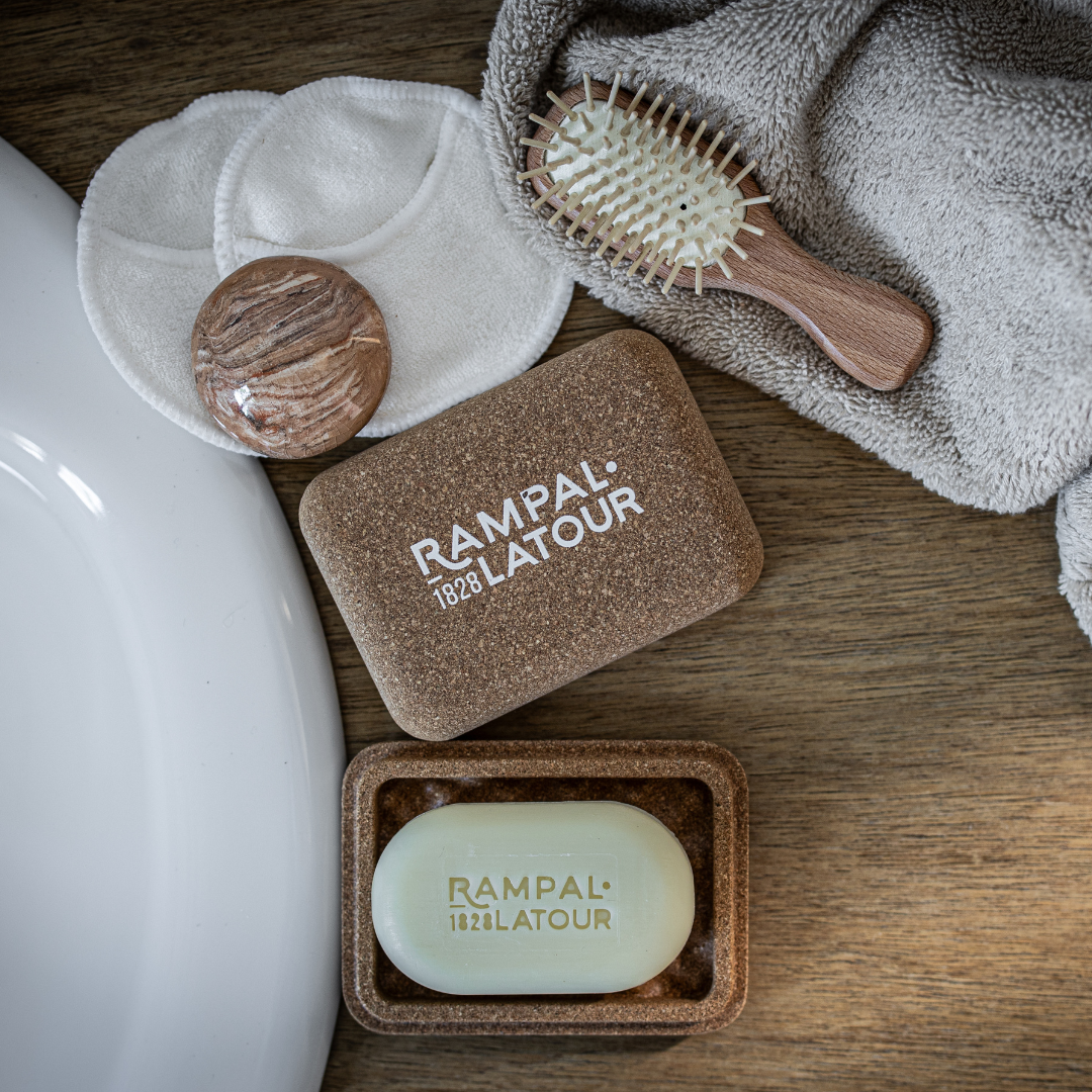 Savon Rampal Latour dans son porte-savon en liège, près de disques démaquillants lavables sur un lavabo
